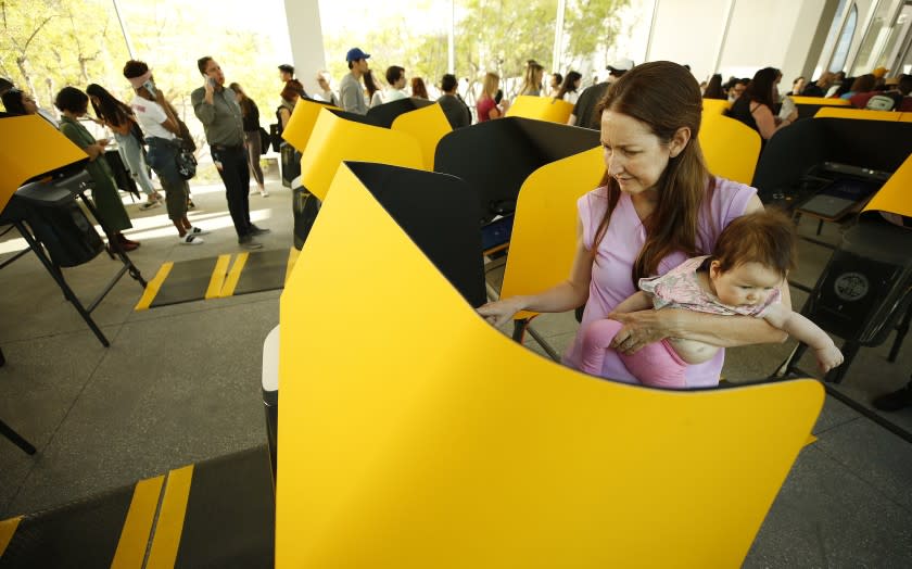 LOS ANGELES, CA - MARCH 3, 2020 Alicia Tamstorf holds her 5 month old Freja Tamstorf while using the new voting machine as a huge line builds with people making their way waiting almost 2 hours in a moving line before they are able to vote using the new voting machines at the UCLA Hammer Museum on Super Tuesday as people make their way to the polls March 3, 2020. (Al Seib / Los Angeles Times)