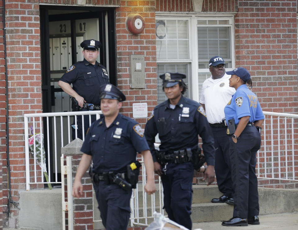 Police officers stand in front of a building where there was a shooting with multiple fatalities in the Queens borough of New York, Tuesday, July 31, 2018. (AP Photo/Seth Wenig)