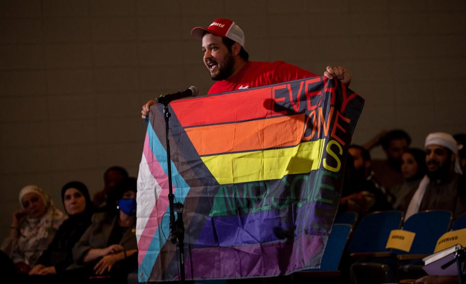 Dylan Wegela, a teacher at a Dearborn high school, holds the Progress Pride Flag during a Dearborn Public Schools board meeting inside Stout Middle School on Thursday, Oct. 13, 2022.