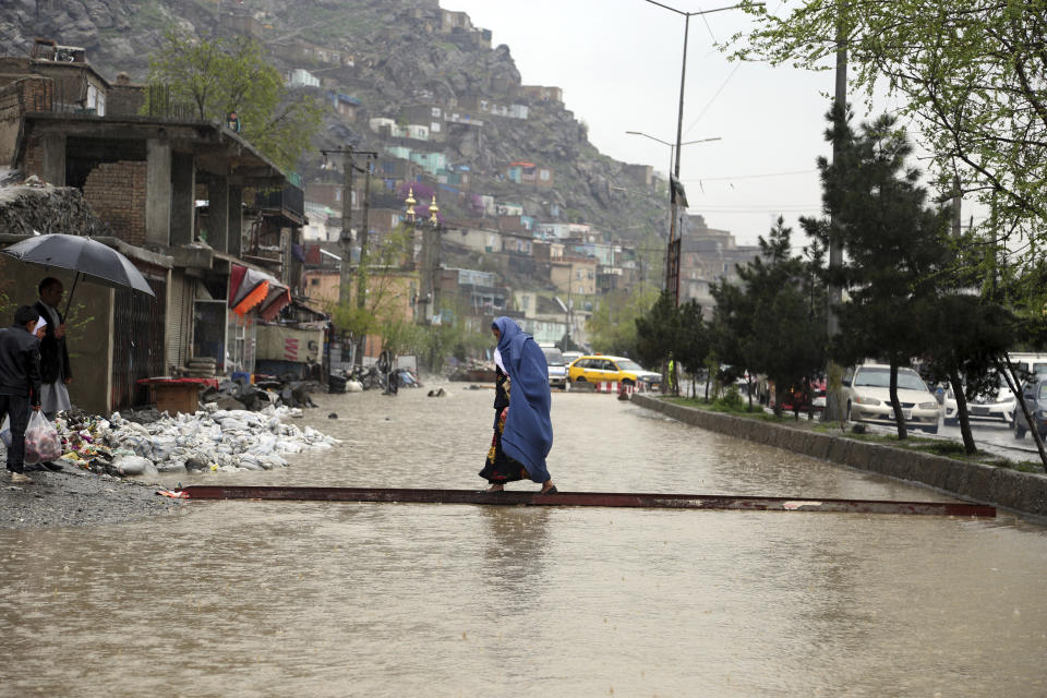 An Afghan woman walks through flood water as heavy rain falls in Kabul, Afghanistan, Tuesday, April 16, 2019. Afghan officials say at least five more people have been killed and 17 are missing as a new wave of heavy rains and flooding swept across the country's western Herat province. (AP Photo/Rahmat Gul)