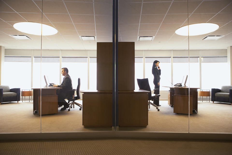 Businessman and businesswoman in back-to-back offices