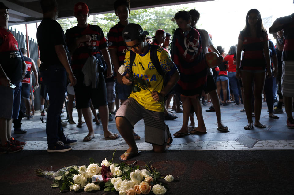 A Flamengo soccer fan places flowers in honor of the teenage players killed by a fire, in Rio de Janeiro, Brazil, Saturday, Feb. 9, 2019. A fire early Friday swept through the sleeping quarters of an academy for Brazil's popular professional soccer club Flamengo, killing several and injuring others, most likely teenage players, authorities said. (AP Photo/Silvia Izquierdo)