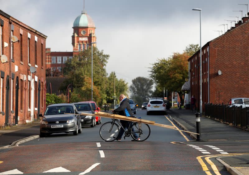 A man pushes a bicycle across a terraced street following the outbreak of the coronavirus disease (COVID-19) in Chadderton, Britain
