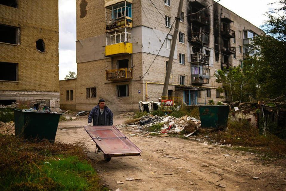 Nikolai, 62, a resident of Izium, Ukraine, attaches a door on a wheelbarrow, to repair his home, Monday, Oct. 3, 2022. (AP Photo/Francisco Seco)