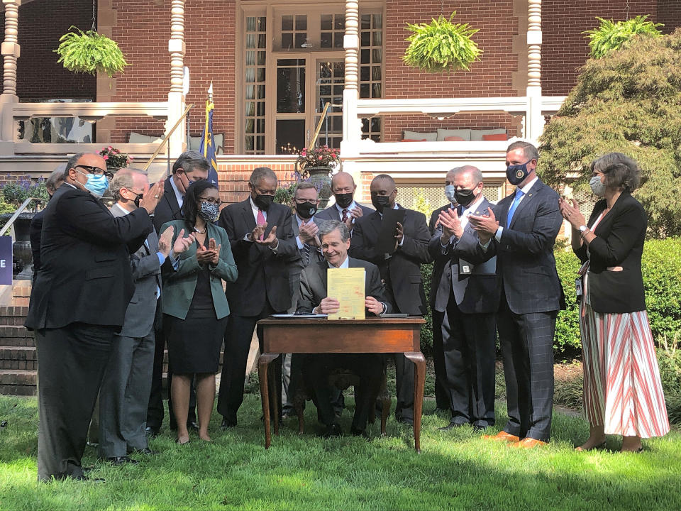 North Carolina Gov. Roy Cooper completes signing into law a major energy bill as several legislators and a Cooper aide applaud during an Executive Mansion ceremony in Raleigh, N.C. Wednesday, Oct. 13, 2021. (AP Photo/Gary D. Robertson)