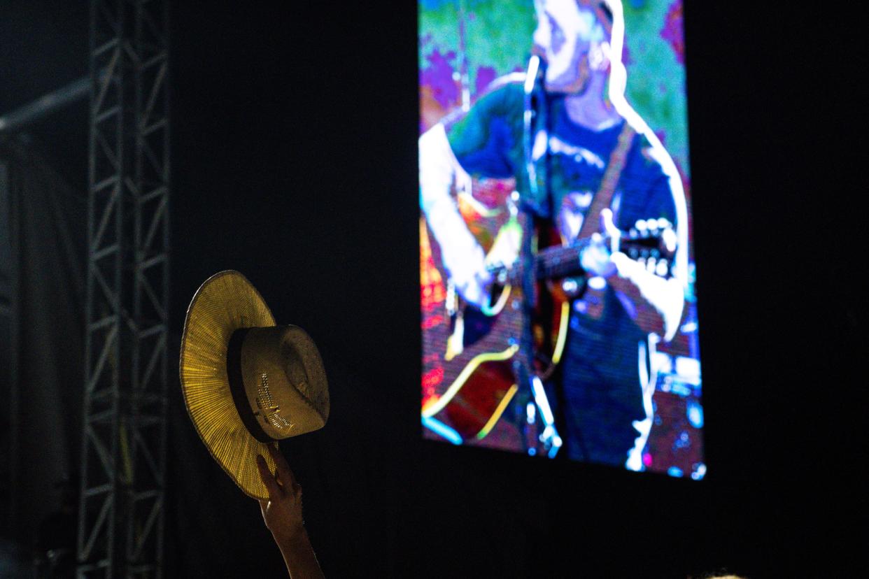 A person holds up a hat as Zach Bryan performs during day two of Hinterland in St. Charles.