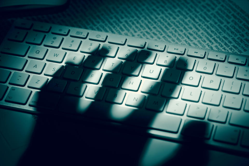 The shadow of an anonymous person’s hand hovers over a computer keyboard. (Image: <span>Dimitris66 via Getty Images)</span>