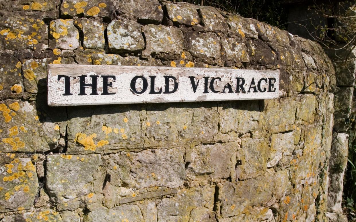 A sign on a weathered wall outside a vicarage in England, UK.