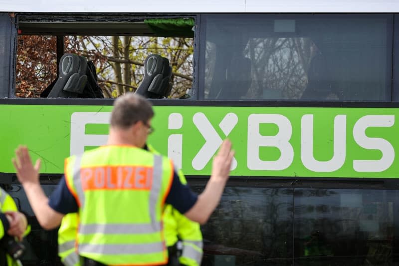 Police officers stand in front of the bus at the scene of the accident on the A9. At least five people died and several were injured in an accident involving a coach on the A9 near Leipzig. Jan Woitas/dpa