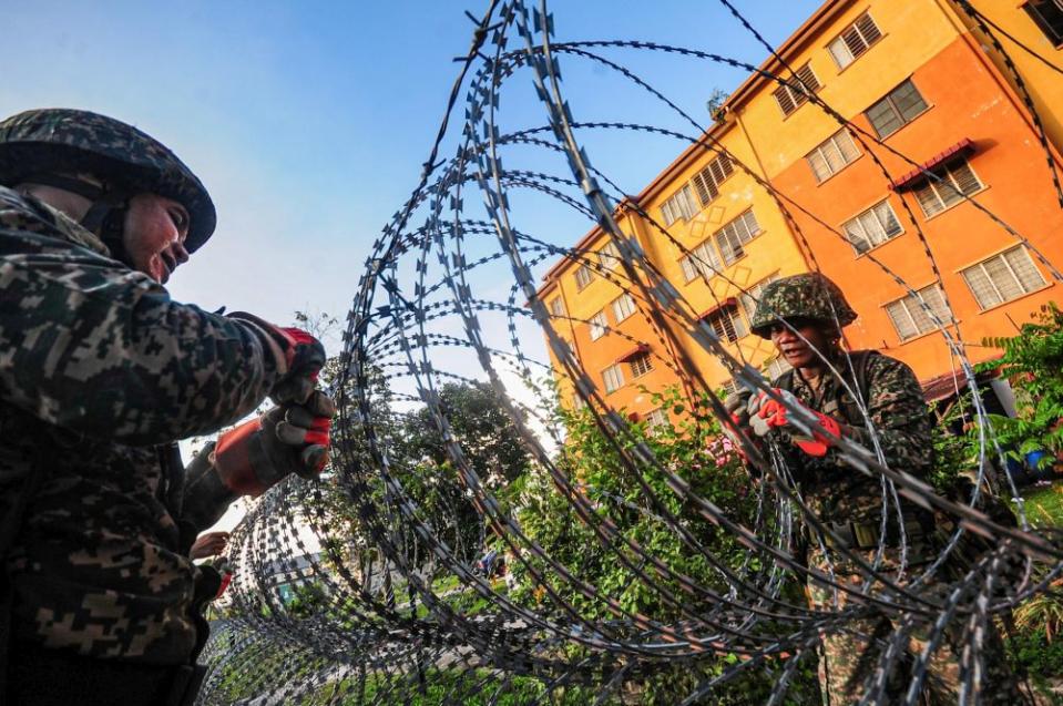 Armed Forces personnel erect barbed wire fencing next to a residential building in Taman Langat Utama June 3, 2020. — Picture by Hari Anggara