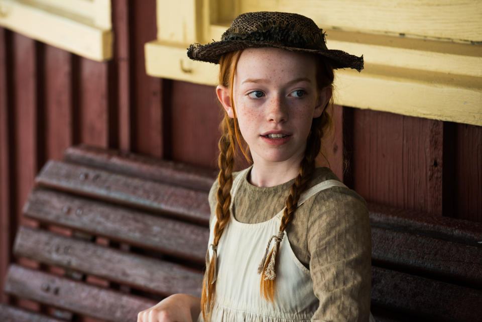 Character Anne from 'Anne of Green Gables' in period clothing with braids and a straw hat