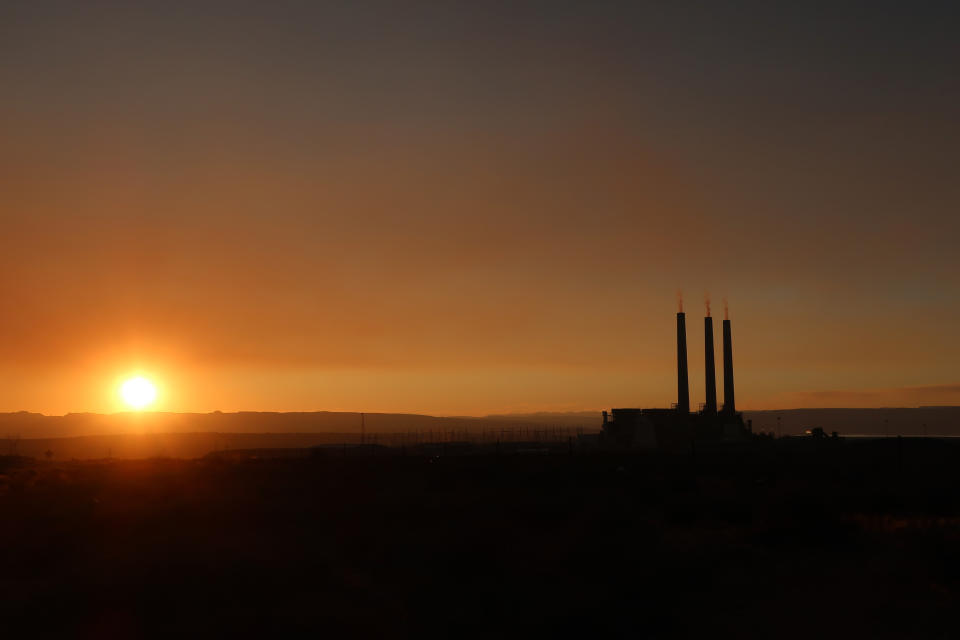 This Aug. 19, 2019, image shows the sun setting behind the coal-fired Navajo Generating Station near Page, Ariz. The power plant will close before the year ends, upending the lives of hundreds of mostly Native American workers who mined coal, loaded it and played a part in producing electricity that powered the American Southwest. (AP Photo/Felicia Fonseca)