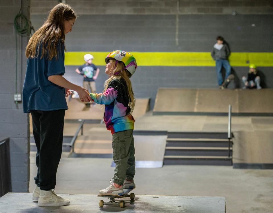 16-year-old Grace Kory, former Q student turned teacher, holds Makayla Schneider’s, 5, hands Sunday, March 5, 2023, as they prepare to go down a ramp together at Q Skatepark in the Stout Army Field neighborhood in Indianapolis. Schneider has been skating for a year and a half and got into the sport alongside her older sister Laila Olivia Schneider, 8.