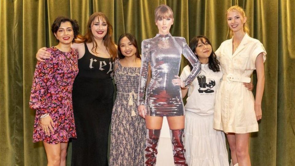 Fans posan con una gigantografía de Taylor Swift.