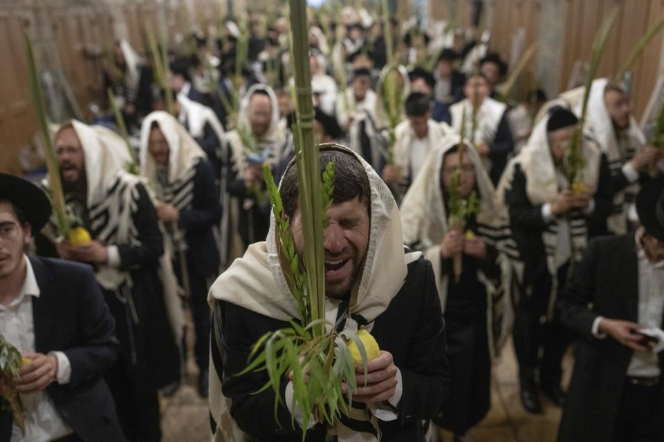 Jewish worshippers pray during the weeklong Jewish holiday of Sukkot, next to one of the gates to the Temple Mount, known to Muslims as the Noble Sanctuary, or the Al-Aqsa Mosque compound, in the Old City of Jerusalem, Wednesday, Oct. 4, 2023. (AP Photo/Ohad Zwigenberg)