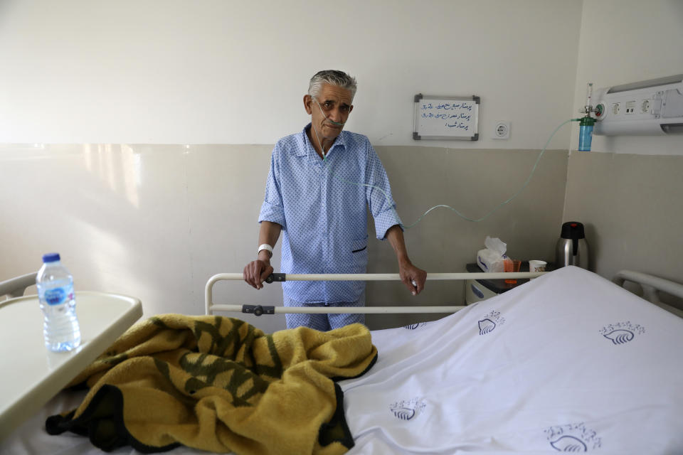 In this Tuesday, June 16, 2020, photo, a COVID-19 patient stands next to his bed at the Shohadaye Tajrish Hospital in Tehran, Iran. After months of fighting the coronavirus, Iran only just saw its highest single-day spike in reported cases after Eid al-Fitr, the holiday that celebrates the end of Ramadan. (AP Photo/Vahid Salemi)