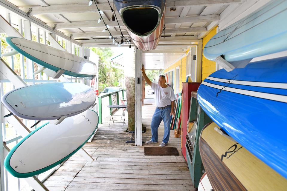 Jim Rodgers gives a tour of some of surfboards featured under the awning of the porch at his Fort George Surf Shop on Heckscher Drive.