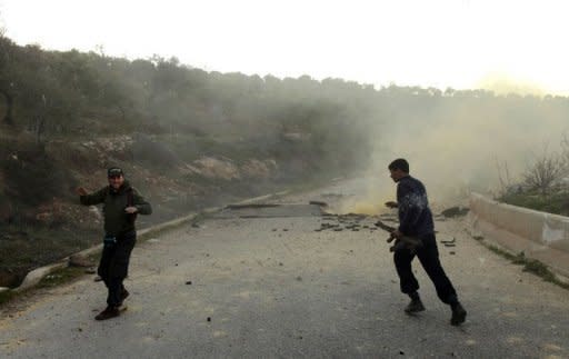 The leader of a group of rebel fighters celebrates after detonating an IED used to cut road access to their stronghold in the northern Syrian province of Idlib on March 20. The UN Security Council demanded Wednesday that Syria immediately implement a peace plan by special envoy Kofi Annan, even as government forces pounded rebel zones around Damascus and Homs