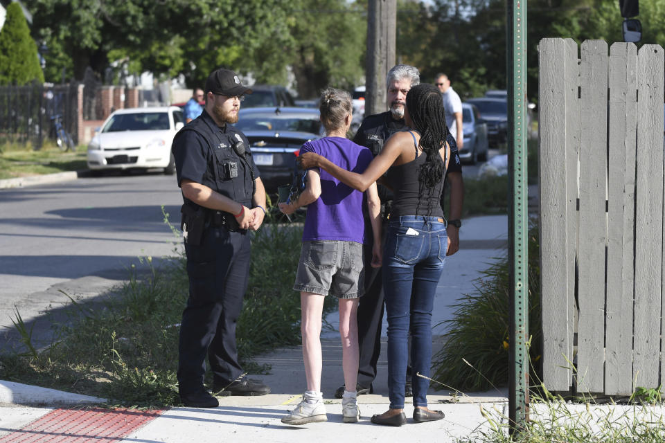 Deborah Golden, center, talks with Detroit police after she tried to render aid to a young girl who later died of her injuries in Detroit on Monday, Aug. 19, 2019. Police say the owner of three dogs is in custody after the animals killed Emma Hernandez, 9, as she rode a bike. The girl's father, Armando Hernandez, says the man was warned that a fence was too flimsy to hold the dogs. (Max Ortiz/Detroit News via AP)