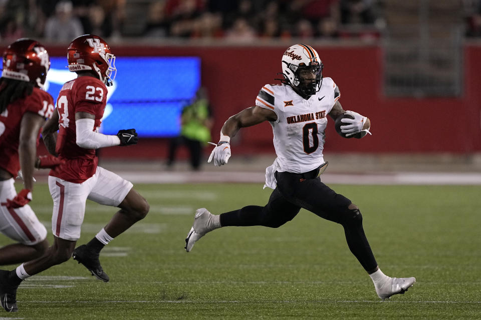 Oklahoma State running back Ollie Gordon II (0) rushes for a gain as Houston defensive back Isaiah Hamilton (23) defends during the second half of an NCAA college football game Saturday, Nov. 18, 2023, in Houston. Oklahoma State won 43-30. (AP Photo/David J. Phillip)