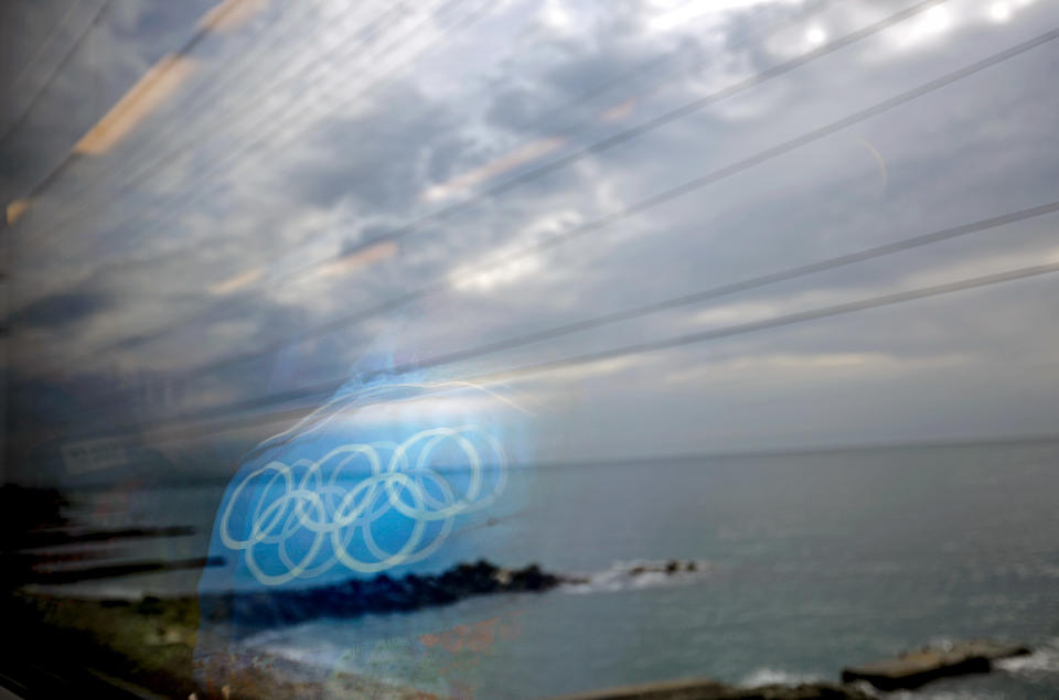 The Olympic rings on the back of a jacket of a worker are reflected in a train window as it travels from the Olympic Park to the Sochi city center along the Black Sea, Monday, Feb. 10, 2014, in Sochi, Russia, home to the 2014 Winter Olympics.