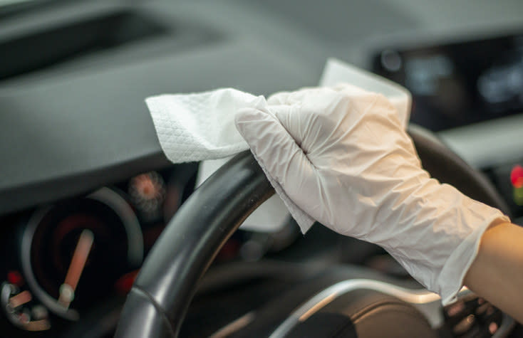 someone using a wipe to clean the steering wheel