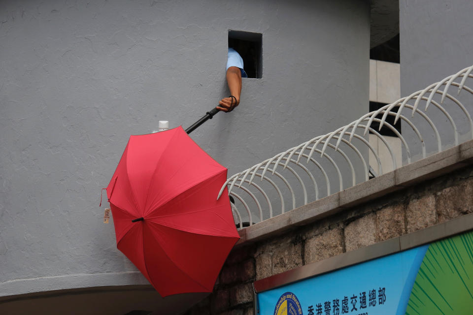 A police officer tries to remove an umbrella blocking the view of security cameras outside the police headquarters in Hong Kong Friday, June 21, 2019. Several hundred mainly student protesters gathered outside Hong Kong government offices Friday morning, with some blocking traffic on a major thoroughfare, after a deadline passed for meeting their demands related to controversial extradition legislation that many see as eroding the territory's judicial independence. (AP Photo/Kin Cheung)