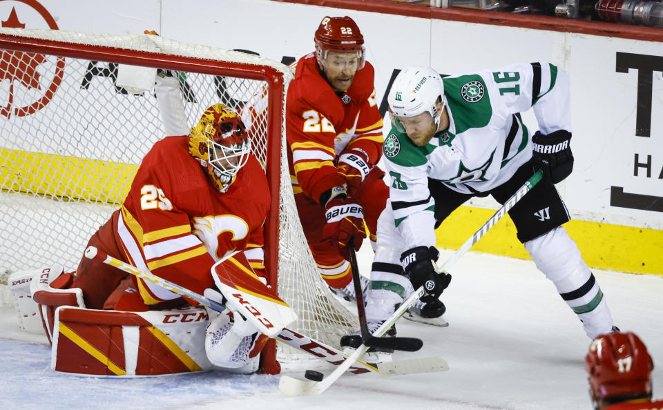 Dallas Stars forward Joe Pavelski, right, tries to get the puck past Calgary Flames goalie Jacob Markstrom, left, as forward Trevor Lewis checks him during first period NHL playoff hockey action in Calgary, Alberta, Sunday, May 15, 2022. (Jeff McIntosh/The Canadian Press via AP)