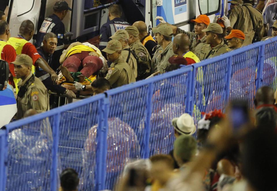 Injured: Firefighters carry a person on a stretcher during Carnival celebrations (AP)