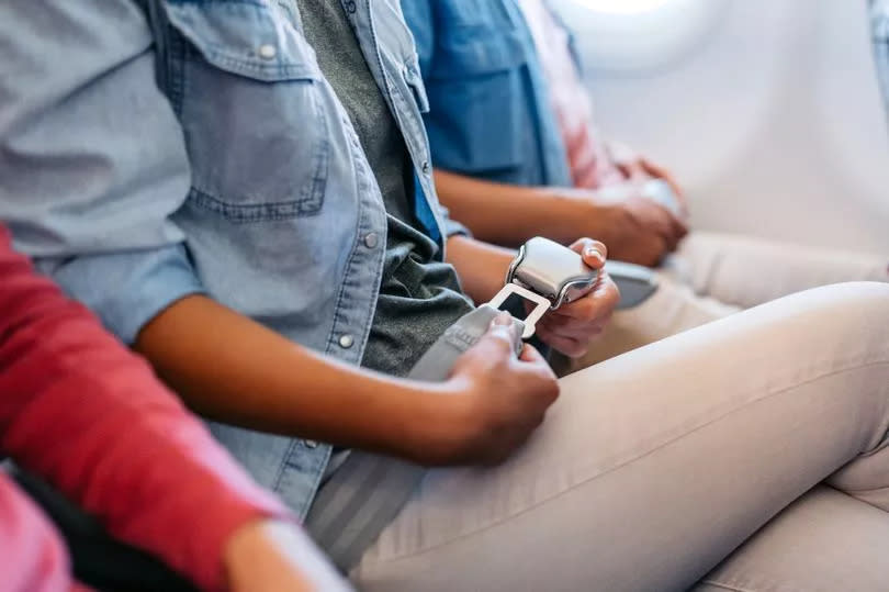 Close-up of a young woman fastening her seatbelt in an airplane