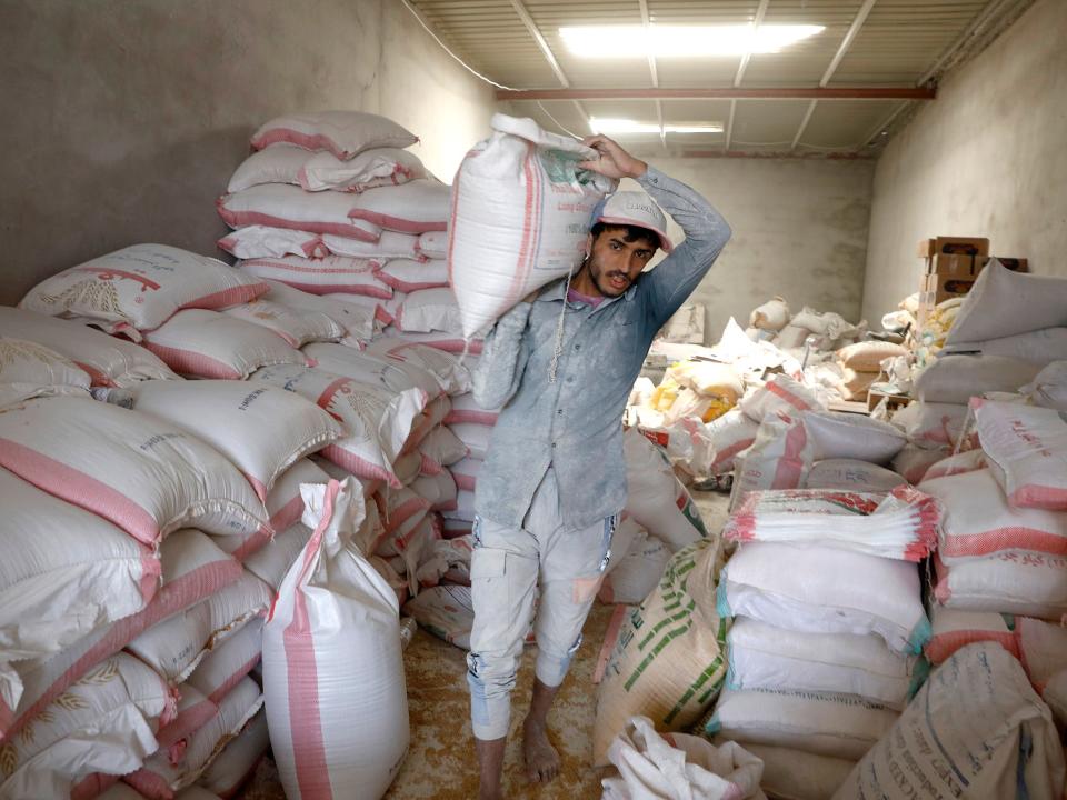 A worker carries a bag of imported wheat grain in Yemen (Yahya Arhab/EPA)