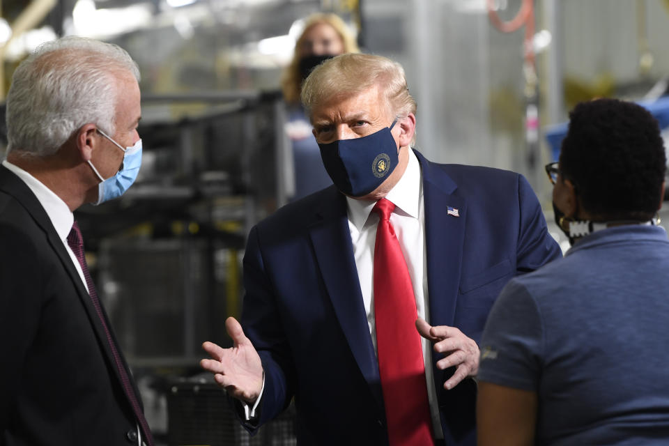 President Donald Trump, center, wears a mask as he talks to Jim Keppler, Whirlpool Corporation Vice President of Integrated Supply Chain and Quality, left, during a tour of the Whirlpool Corporation facility in Clyde, Ohio, Thursday, Aug. 6, 2020. (AP Photo/Susan Walsh)