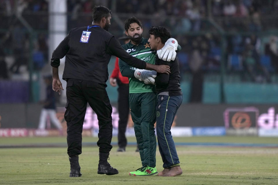 Pakistan's Mohammad Rizwan, center, talks with a pitch invader as police officer prepare to take way him during the second one-day international cricket match between Pakistan and New Zealand, in Karachi, Pakistan, Wednesday, Jan. 11, 2023. (AP Photo/Fareed Khan)