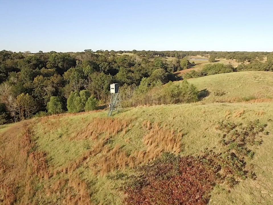 A photo of rolling hills and trees and a watch tower on Terry Bradshaw's ranch.