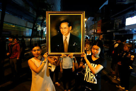 Women pose with a portrait of Thailand's King Bhumibol Adulyadej, as others line up to hold the portrait, after the announcement of the king's death, outside Siriraj hospital in Bangkok, Thailand October 13, 2016. REUTERS/Jorge Silva