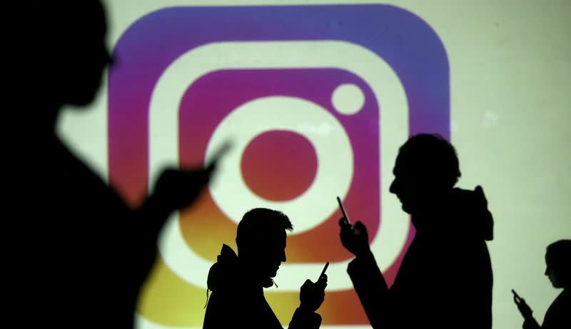 FILE PHOTO: FILE PHOTO: Silhouettes of mobile users are seen next to a screen projection of Instagram logo in this picture illustration