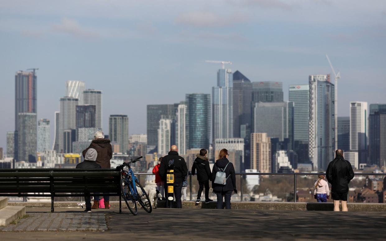 People look out to the Canary Wharf from across the Thames