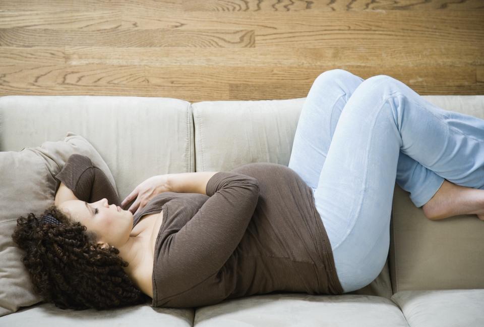 Pregnant African woman sleeping on sofa