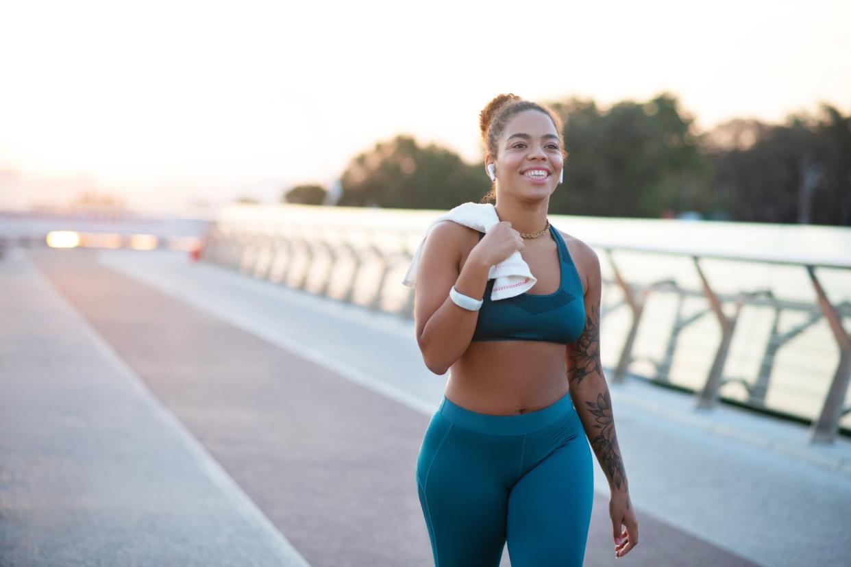 Woman going home. Tattooed young woman holding towel while going home after running in the morning