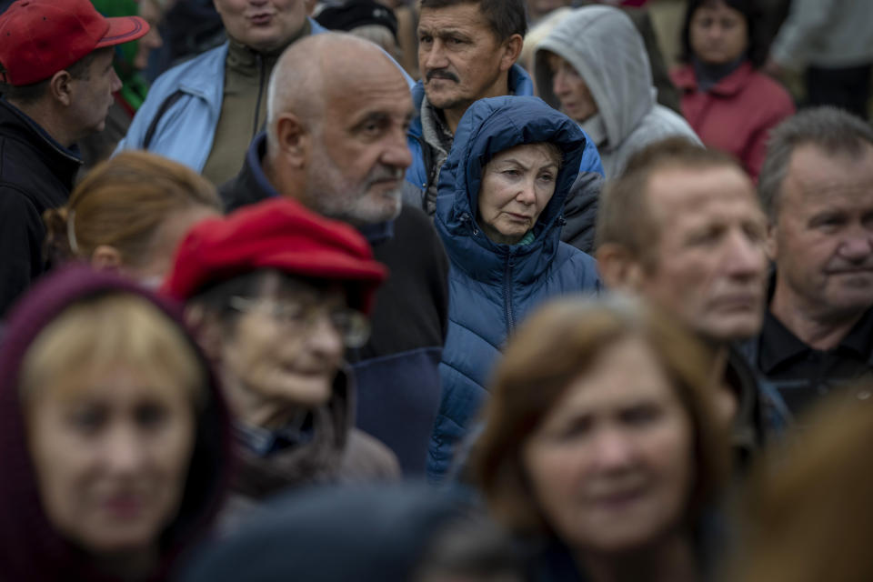 People queue to receive a daily ration of bread in a school in Mykolaiv, Tuesday, Oct. 25, 2022. Mykolaiv residents pick up bread from the only food distribution point in Varvarivka, a Mykolaiv district where thousands of people live. One person is allowed to receive free bread just once in three days. (AP Photo/Emilio Morenatti)