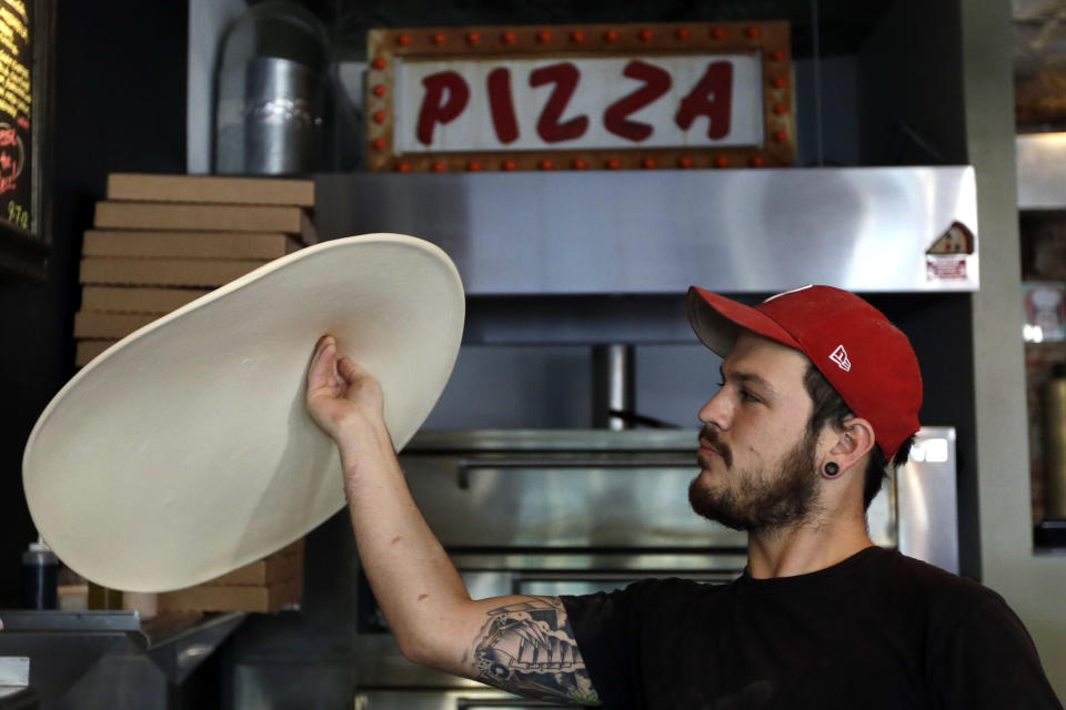 In this Wednesday, Sept. 12, 2012 photo, Joseph Hunter tosses a pizza in the air at Pizza Brain in Philadelphia. Hundreds of people turned out for the grand opening of Pizza Brain this month in Philadelphia's Fishtown neighborhood. It's a restaurant where visitors can eat a slice or two of artisan pie while gawking at a pizza-related photos, records, knickknacks and videos. (AP Photo/Matt Rourke)