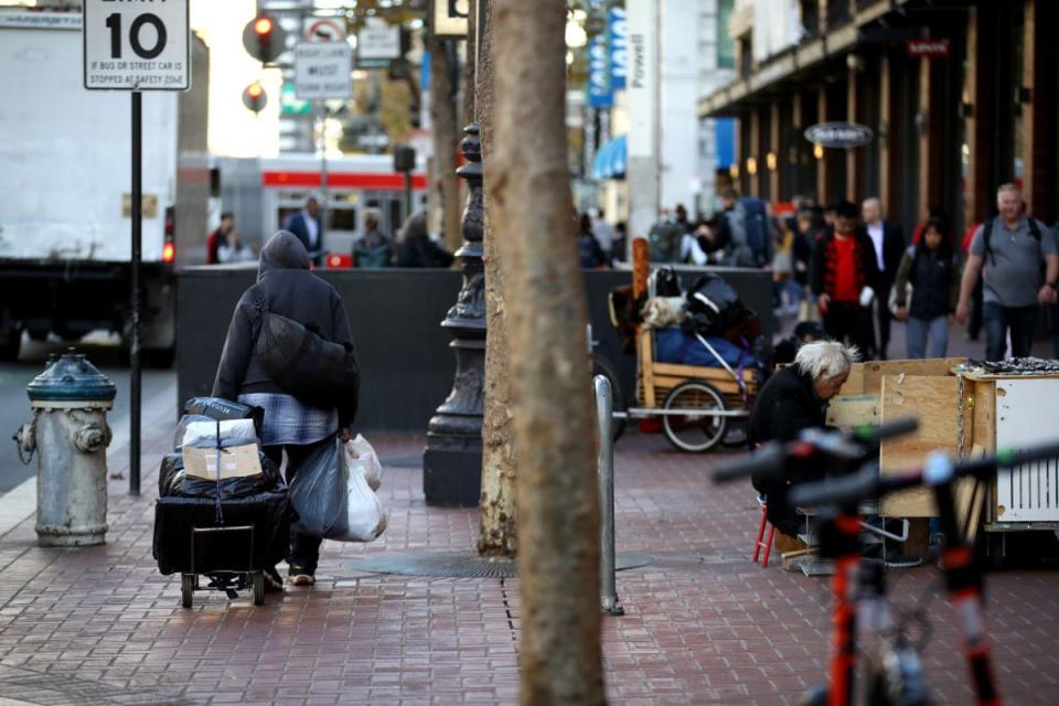 A homeless man pulls a cart with his belongings on 25 November 2019 in San Francisco, California (Getty Images)