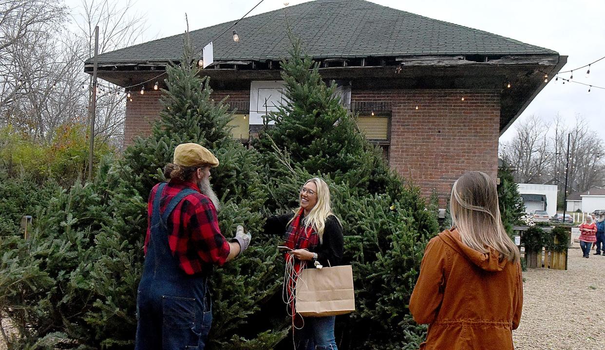 Kim Martin, right, watches as Jake Allen sells a Canadian Balsam Fir Christmas tree to Kristina Bright, all of Fulton, last year at the inaugural Christmas Market at the Fulton Train Depot.