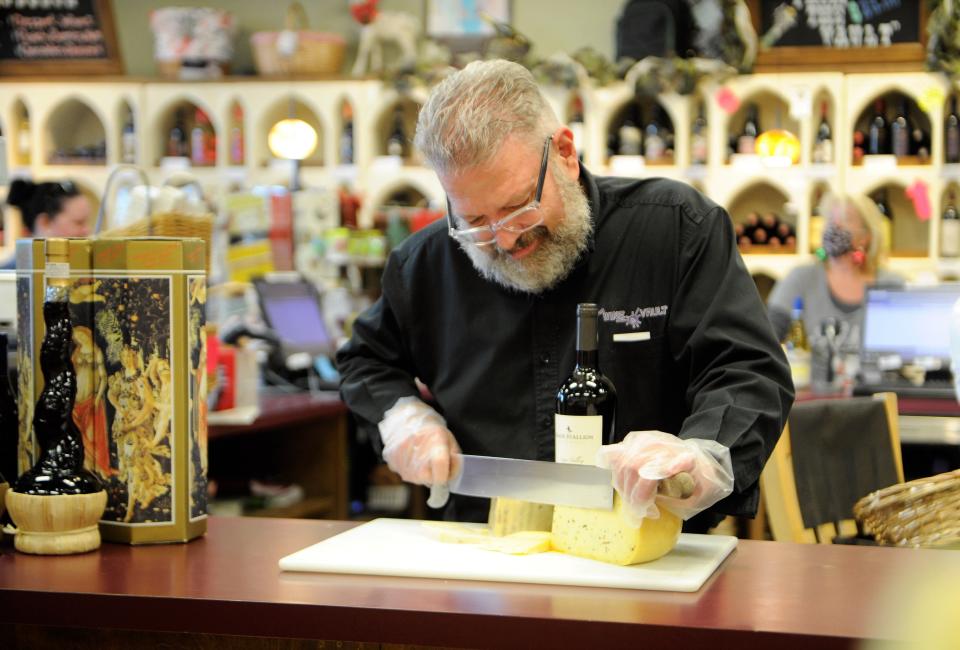 Mark Fox cuts cheese to sample at The Wine Vault on Tuesday, Dec. 22, 2021.