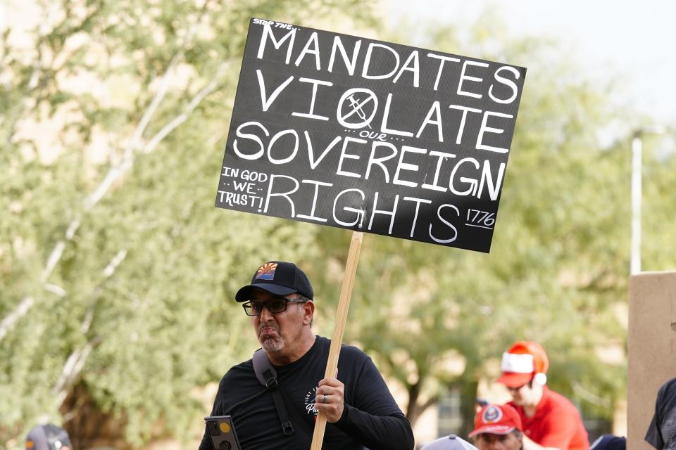 FILE - One of many anti-vaccine mandate activists holds a sign during a rally outside Phoenix City Council chambers as the city paused implementation of a federal COVID-19 vaccine mandate for the 14,000 city workers, Tuesday, Dec. 7, 2021, in Phoenix. On Friday, Dec. 17, 2021, a federal appeals court panel allowed President Joe Biden's COVID-19 vaccine mandate for larger private employers to move ahead. (AP Photo/Ross D. Franklin, File)