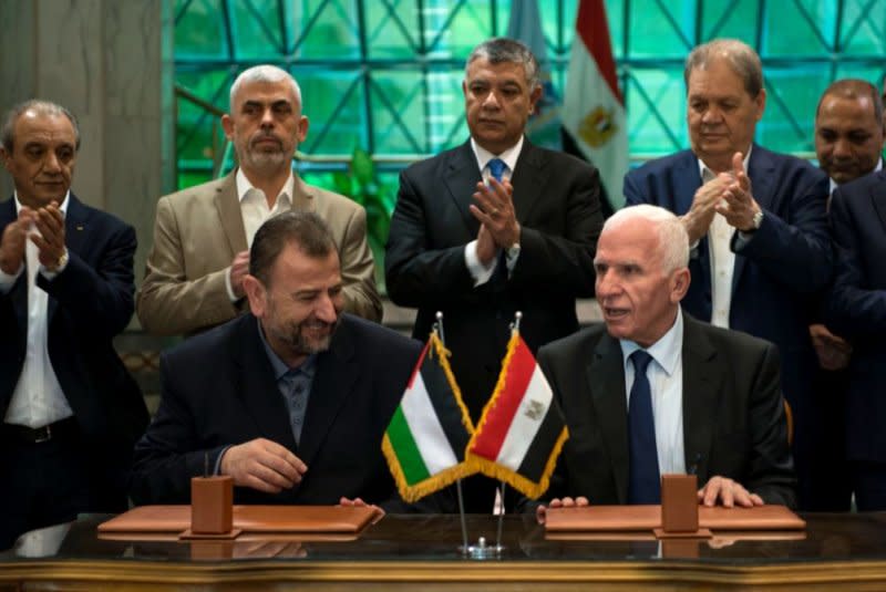 Hamas deputy politburo leader Saleh al-Arouri (L) and Azam al-Ahmed (R) of the Fatah Central Committee sign an agreement between the two Palestinian factions as Egyptian Intelligence Minister Khalid Fawzi (C, back) looks, in Cairo in 2017. File Photo by EPA-EFE