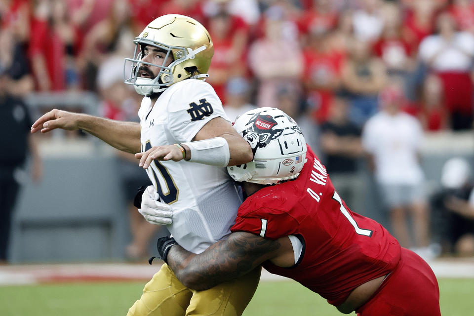 Notre Dame's Sam Hartman (10) is hit by North Carolina State's Davin Vann (1) after passing the ball during the first half of an NCAA college football game in Raleigh, N.C., Saturday, Sept. 9, 2023. (AP Photo/Karl B DeBlaker)