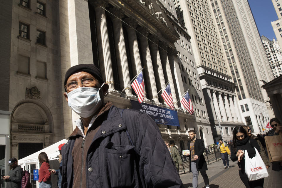 FILE - In this Monday, March 9, 2020 file photo, a man wears a mask as he walks past the New York Stock Exchange, amid concerns of the COVID-19 coronavirus outbreak. (AP Photo/Mark Lennihan, File)