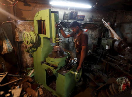 A worker operates a slotting machine as he makes keyways on gears at a workshop in Mumbai, May 27, 2015. REUTERS/Shailesh Andrade