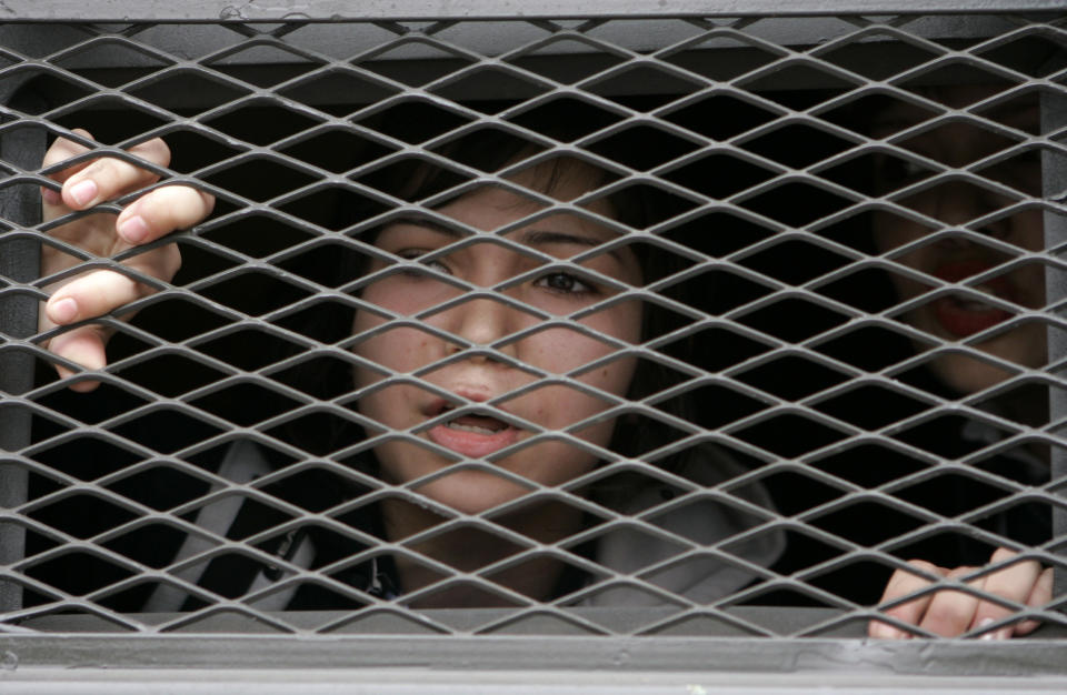 ARCHIVO - En esta imagen de archivo del 18 de octubre de 2006, una estudiante de secundaria corea lemas desde la ventana de un autobús policial tras ser detenida durante una protesta contra el gobierno en Santiago de Chile. (AP Foto/Santiago Llanquin, Archivo)